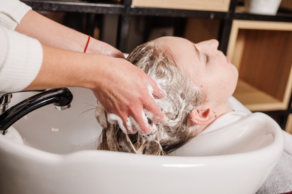 a master in a beauty salon washes a client's hair with shampoo for hair care in a beauty salon
