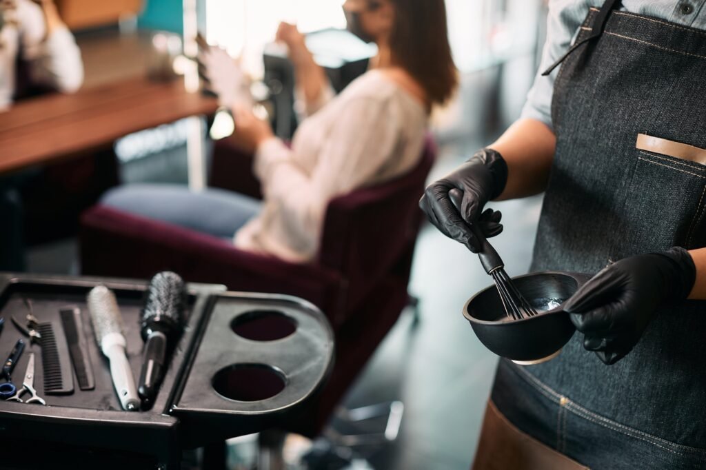 Close-up of hairstylist mixing hair dye while working at the salon.